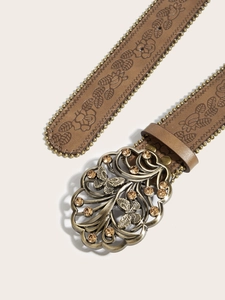 Détail d'une ceinture en cuir marron gaufré avec boucle papillon en bronze et strass