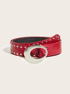 Detail view of red faux-leather belt with crocodile pattern, rivets and silver oval buckle