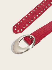 Close-up of red crocodile texture leather belt with silver rivets and oval metal buckle
