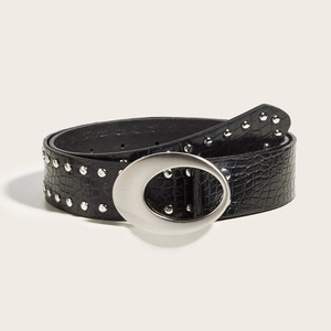 Close-up of black crocodile leather belt featuring silver studs and large oval buckle