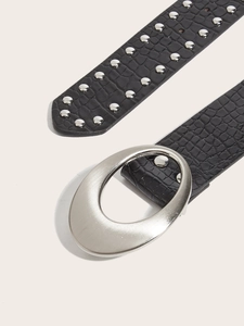 Detail of black crocodile texture belt with silver rivets and oval metal buckle