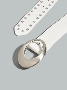 Close-up of white crocodile pattern belt with silver oval buckle and metal studs