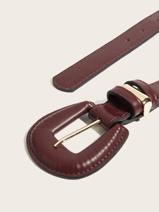Detailed close-up of dark red leather belt with large covered buckle and gold metallic pin