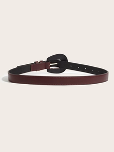 Detail of burgundy leather belt with black shield buckle and gold metallic pin closure