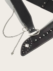 Détail d'une ceinture punk noire avec chaînes argentées, rivets et boucle ornée de strass