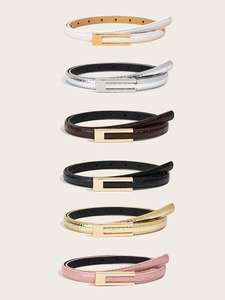 Detailed row of slim women's faux leather belts featuring elegant crocodile texture pattern
