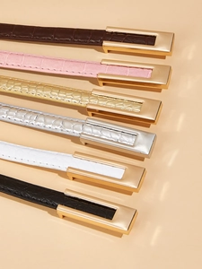 Detail view of thin belts with crocodile pattern and metallic buckle in diverse colors