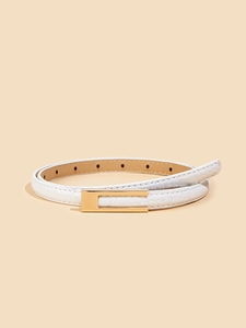 Detail of slim white leather belt with crocodile texture and gold-tone metal buckle