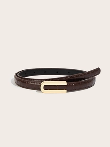 Macro view of dark brown faux crocodile leather belt texture and gold U-shaped buckle