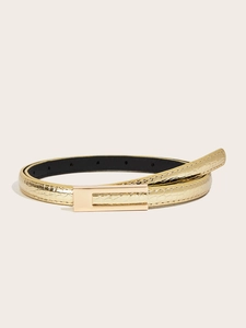 Detail view of gold slim belt featuring embossed crocodile texture and a metal buckle