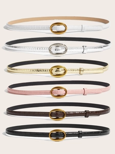Detailed view of six faux leather belts with crocodile pattern and oval metal buckles