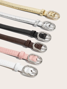 Detail view of slim belts with crocodile pattern and rhinestone encrusted oval buckles