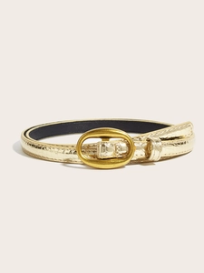Detailed macro view of thin gold belt featuring crocodile pattern and oval buckle