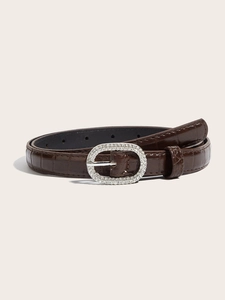 Close-up of brown crocodile texture belt with sparkling rhinestone oval silver buckle
