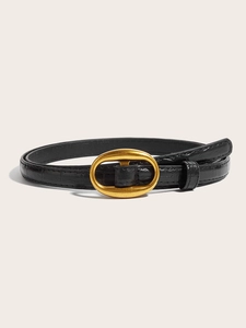 Detail of slim black leather belt with crocodile embossing and golden oval metal buckle