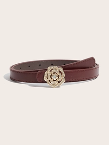 Détail d'une ceinture fine en cuir rouge avec boucle rose dorée ornée de strass