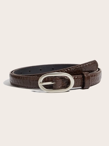 Détail d'une ceinture marron foncé en simili crocodile avec boucle ovale argentée