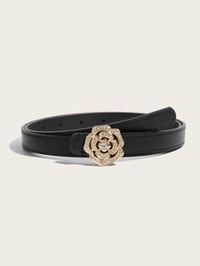 Détail d'une ceinture en cuir noir avec boucle fleur de camélia dorée et strass