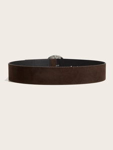 Détail macro de la large ceinture en daim marron foncé avec boucle en métal argenté