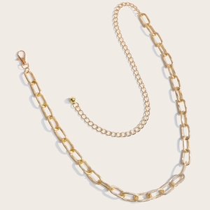 Detailed view of the bright gold hollow metal chain belt with oval links and lobster clasp