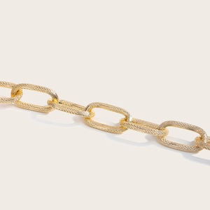 Macro shot of gold hollow oval link chain belt with detailed stardust metal texture