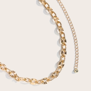 Detailed close-up of golden hollow metal waist chain with sunburst texture links