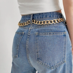 Detail of chunky gold chain link belt on blue denim jeans for punk rock fashion style