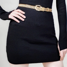 Detailed view of multilayer gold chain belt with oval buckle on black dress