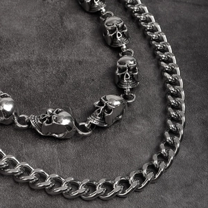 Macro detail of punk skull waist chain with chunky silver cuban links on stone background