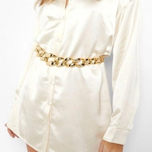 Detailed view of a gold double-layer chain belt with dragon pendant on white fabric