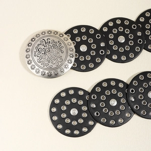 Detail showing vintage silver embossed metal buckle and black leather disk belt design