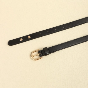 Close-up of a black punk leather belt with a gold horseshoe buckle and metal studs
