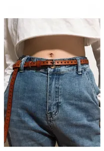 Brown leather belt with heart cutouts and metal buckle styled on blue denim jeans