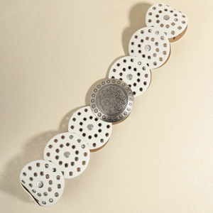 Detail of western vintage belt showing white leather discs and ornate floral metal buckle