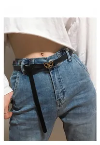 Gros plan sur une fine ceinture en cuir noir avec boucle dorée en forme de papillon