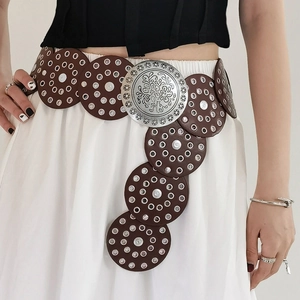 Detail of vintage Western leather belt featuring carved silver buckle and metal grommets