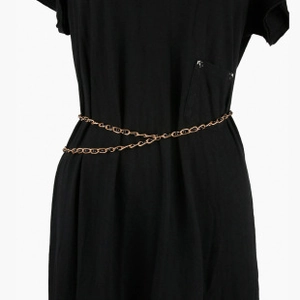 Detail of a thin gold metal waist chain with small oval links styled on a black dress