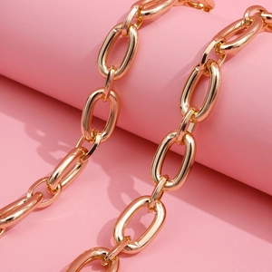 Exaggerated shiny gold metal body chain with chunky oval links on a pink stand