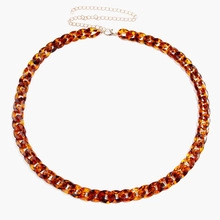 Detail of leopard print acrylic chain belt featuring tortoise shell texture and metal clasp