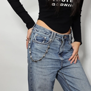 Detail of silver geometric punk waist chain with metal hooks on blue denim jeans