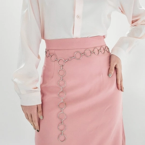 Detail of silver metal ring chain belt on model wearing white shirt and pink skirt