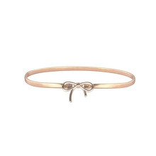 Detail eines roségoldenen elastischen Metallgürtels mit einer zarten Schleifen-Zierschnalle