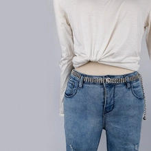 Detailaufnahme der zwelagigen silbernen Blattkette mit Strasssteinen auf Jeans