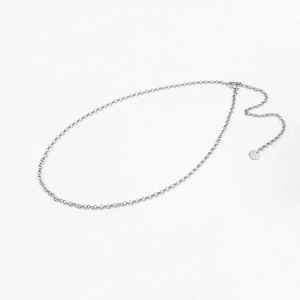 Détail de la chaîne de taille en métal argenté avec pendentif rond sur fond blanc