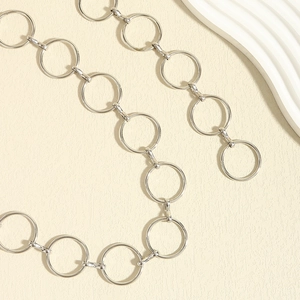 Detail shot of silver metal circular ring chain belt on textured beige background