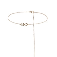 Detail view of a gold infinity charm and script letter on a dainty spring-style waist chain