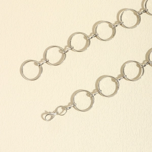 Detail of silver metal body chain featuring circular rings and lobster clasp closure