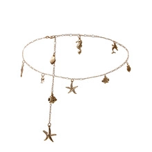Détails d'une chaîne dorée thème océan avec pendentifs étoile de mer, hippocampe et dauphin