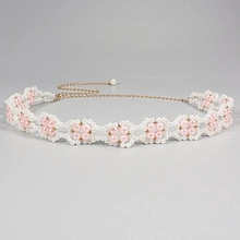 Detailed close-up of handmade white beaded flower chain with pink faux pearl centers