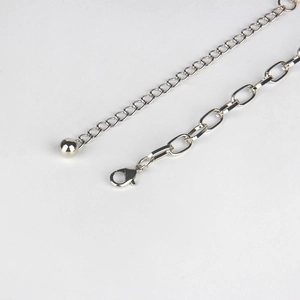 Detail of silver metal waist chain showing lobster clasp and polished ball pendant design